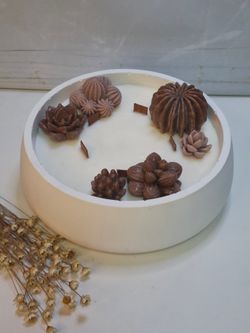 Vela aromática artesanal grande en recipiente blanco decorado con cactus y suculentas
