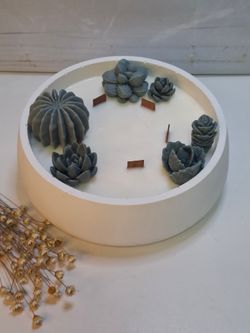 Vela aromática artesanal grande en recipiente blanco decorado con cactus y suculentas