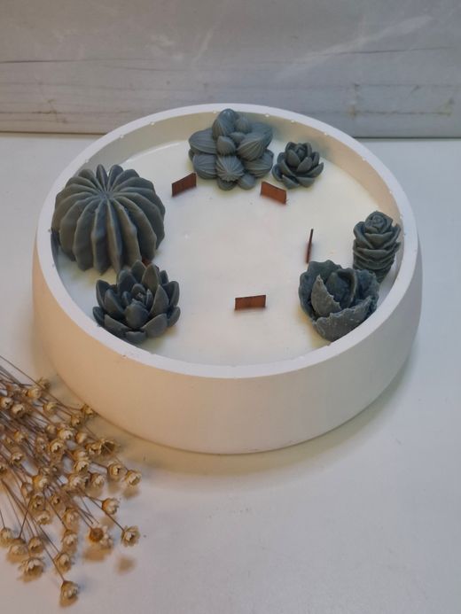 Vela aromática artesanal grande en recipiente blanco decorado con cactus y suculentas