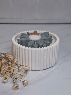 Vela decorativa con flor en recipiente blanco rayado