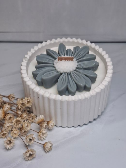Vela decorativa con flor en recipiente blanco rayado