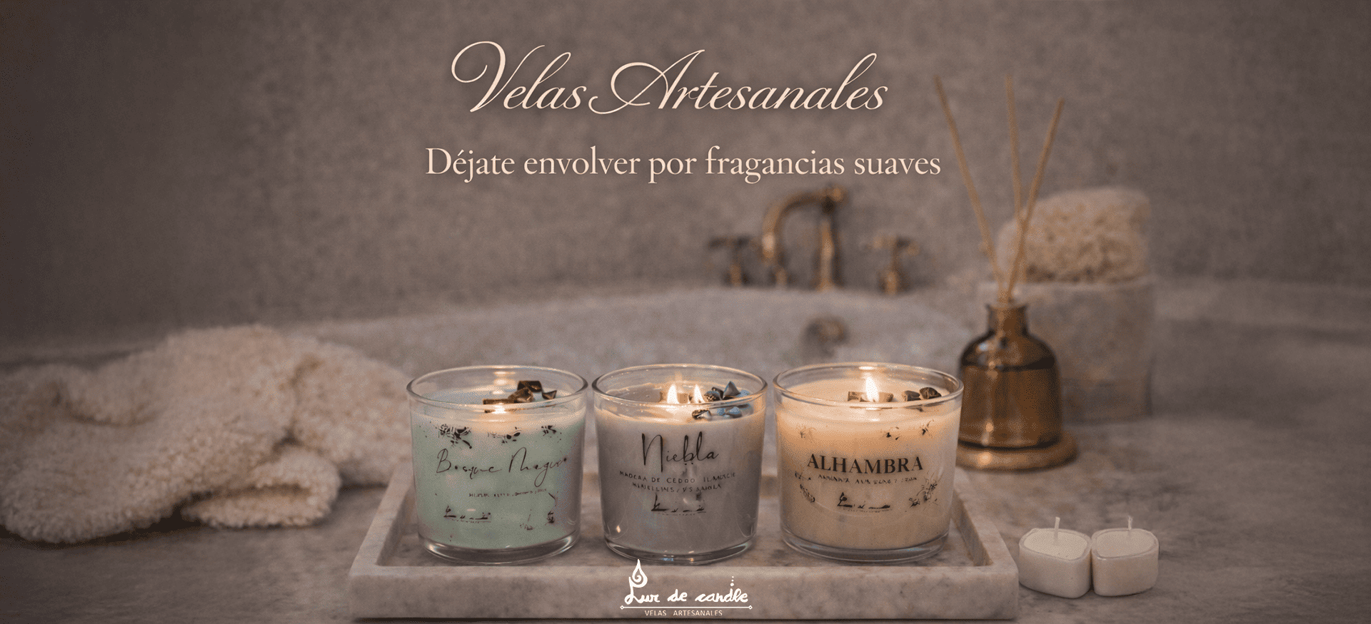 Banner de Luz de Candle con cuatro velas clásicas en vaso de cristal —Alhambra, Wet Wood, Bosque Mágico y Niebla— sobre fondo de mármol gris, acompañado del mensaje “Decora tu hogar con aromas únicos, 100 % naturales y hechos a mano”.